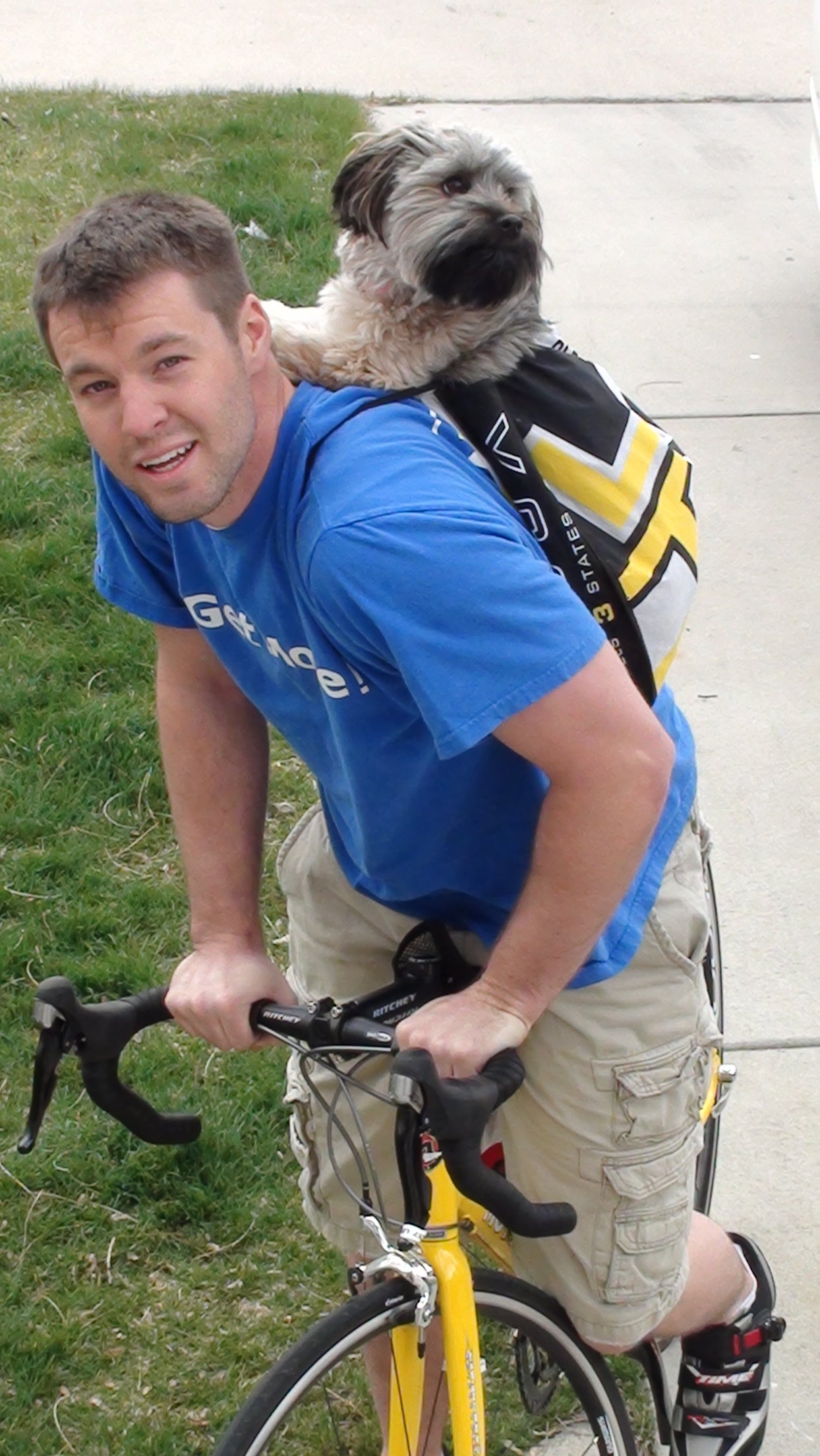 Joseph biking with Daisy in a drawstring backpack